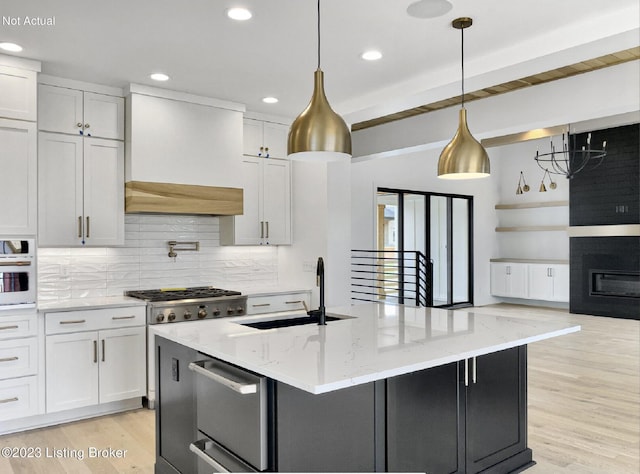 kitchen featuring white cabinetry, hanging light fixtures, light stone counters, and sink