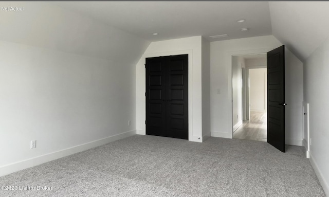 unfurnished bedroom with vaulted ceiling and carpet