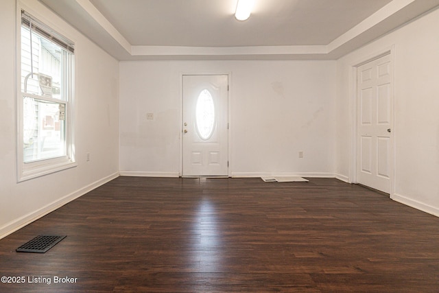 entryway with a tray ceiling and dark wood-type flooring