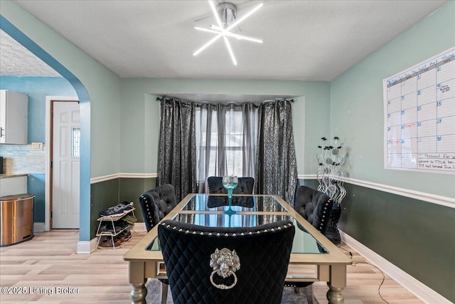 dining space featuring light wood-type flooring and a textured ceiling