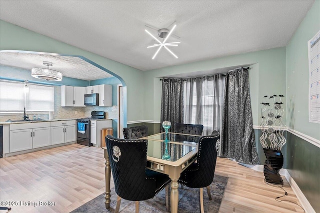 dining space with light hardwood / wood-style floors, sink, and a healthy amount of sunlight