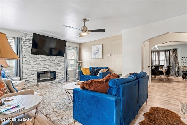 living room featuring light hardwood / wood-style flooring, ceiling fan, and a fireplace