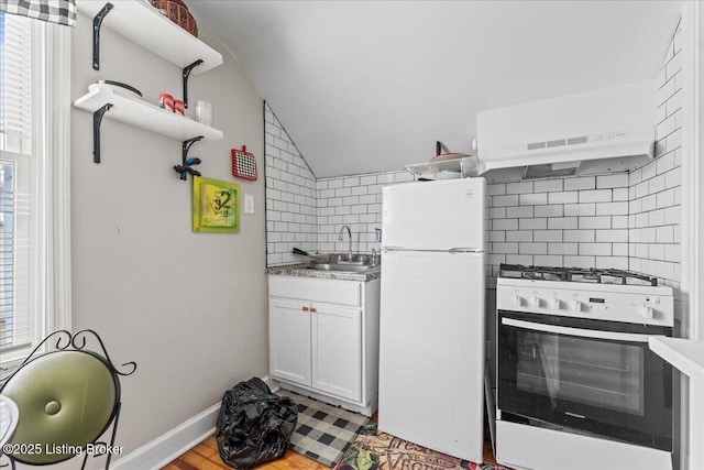 kitchen with tasteful backsplash, white appliances, vaulted ceiling, sink, and white cabinetry