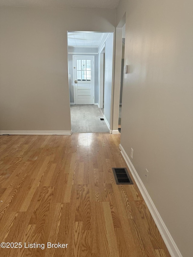 hall featuring light wood finished floors, visible vents, and baseboards