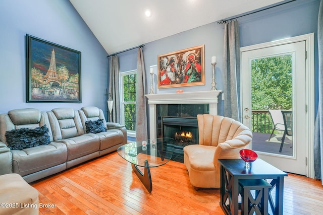 living room featuring vaulted ceiling, hardwood / wood-style floors, and a tile fireplace