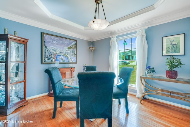 dining space with ornamental molding and light hardwood / wood-style floors