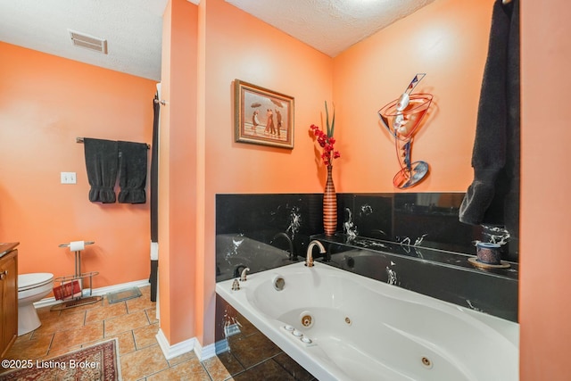 bathroom with tile patterned flooring, a tub to relax in, a textured ceiling, and toilet