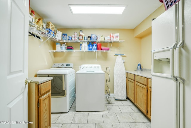 laundry area featuring light tile patterned flooring, cabinets, and washer and clothes dryer