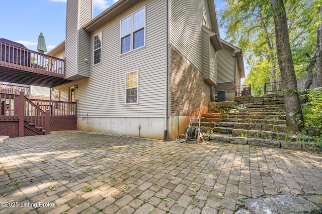 back of property featuring a wooden deck and a patio