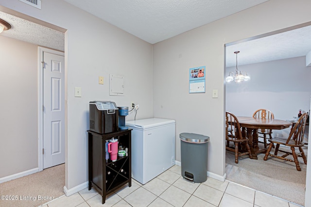 laundry room featuring light carpet, a notable chandelier, and a textured ceiling