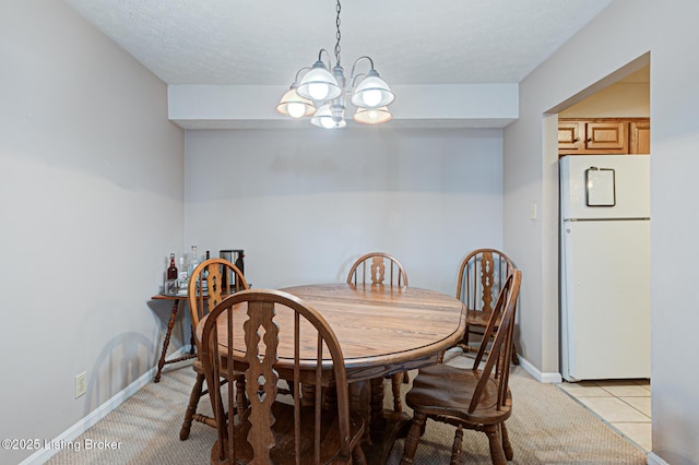 tiled dining room featuring a textured ceiling and a chandelier