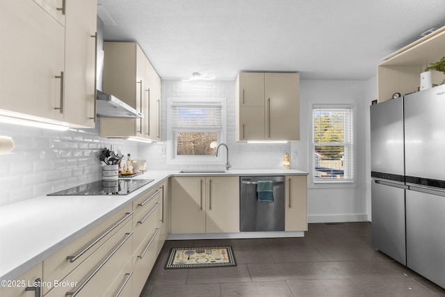 kitchen featuring sink, stainless steel appliances, decorative backsplash, cream cabinetry, and wall chimney exhaust hood