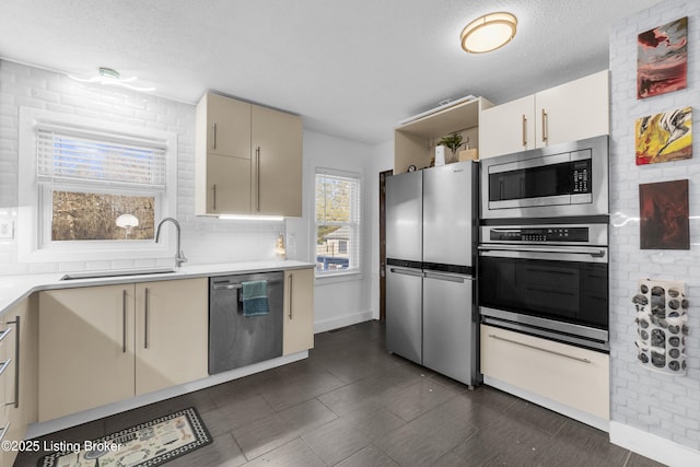 kitchen with sink, stainless steel appliances, tasteful backsplash, a textured ceiling, and cream cabinetry