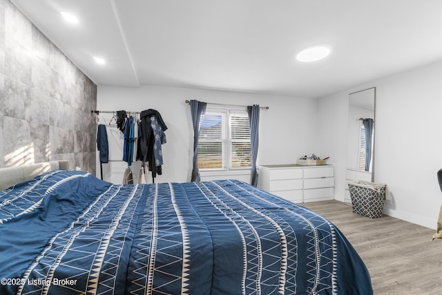 bedroom with wood-type flooring, multiple windows, and tile walls