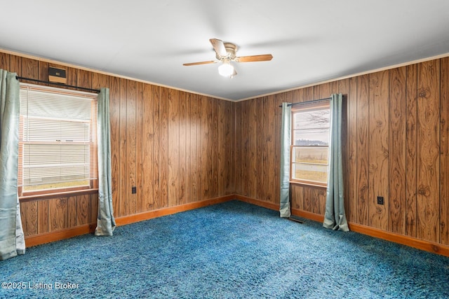 carpeted spare room featuring ceiling fan and wooden walls