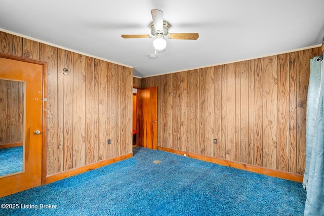 carpeted spare room featuring ceiling fan and wooden walls