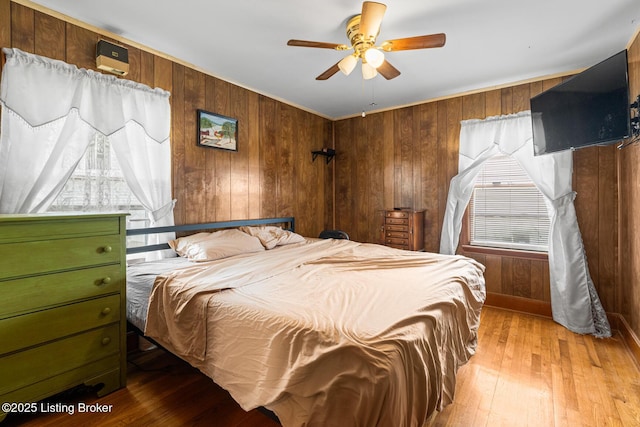 bedroom featuring hardwood / wood-style flooring, wooden walls, and ceiling fan