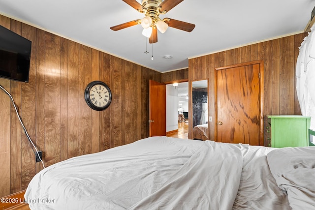 bedroom with ceiling fan and wood walls