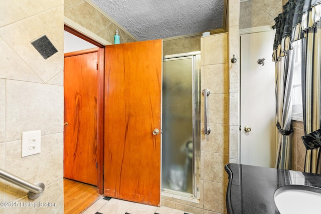 bathroom with an enclosed shower, tile walls, and a textured ceiling