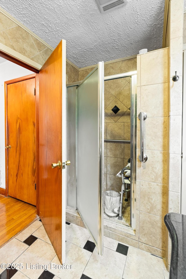 bathroom with walk in shower, tile patterned floors, and a textured ceiling