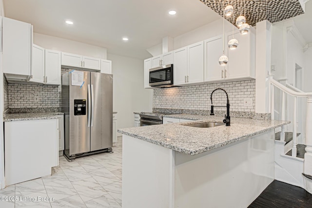 kitchen featuring appliances with stainless steel finishes, sink, white cabinets, and decorative light fixtures