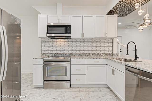 kitchen featuring sink, white cabinets, ceiling fan, stainless steel appliances, and light stone countertops