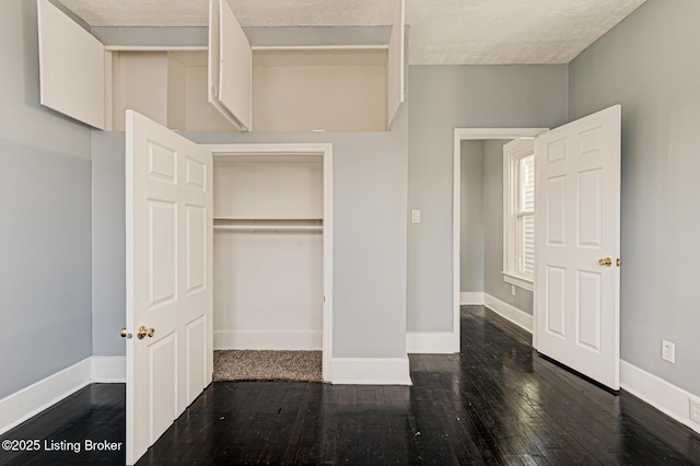 unfurnished bedroom with dark hardwood / wood-style floors, a textured ceiling, and a closet