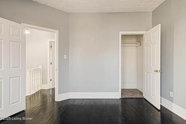 unfurnished bedroom with dark wood-type flooring, a closet, and a textured ceiling