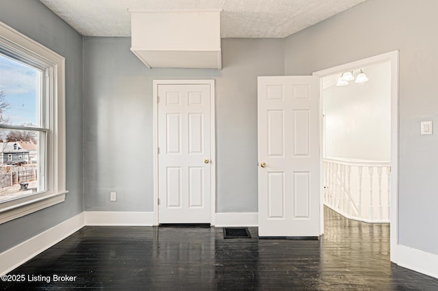 unfurnished bedroom with a textured ceiling and dark hardwood / wood-style flooring