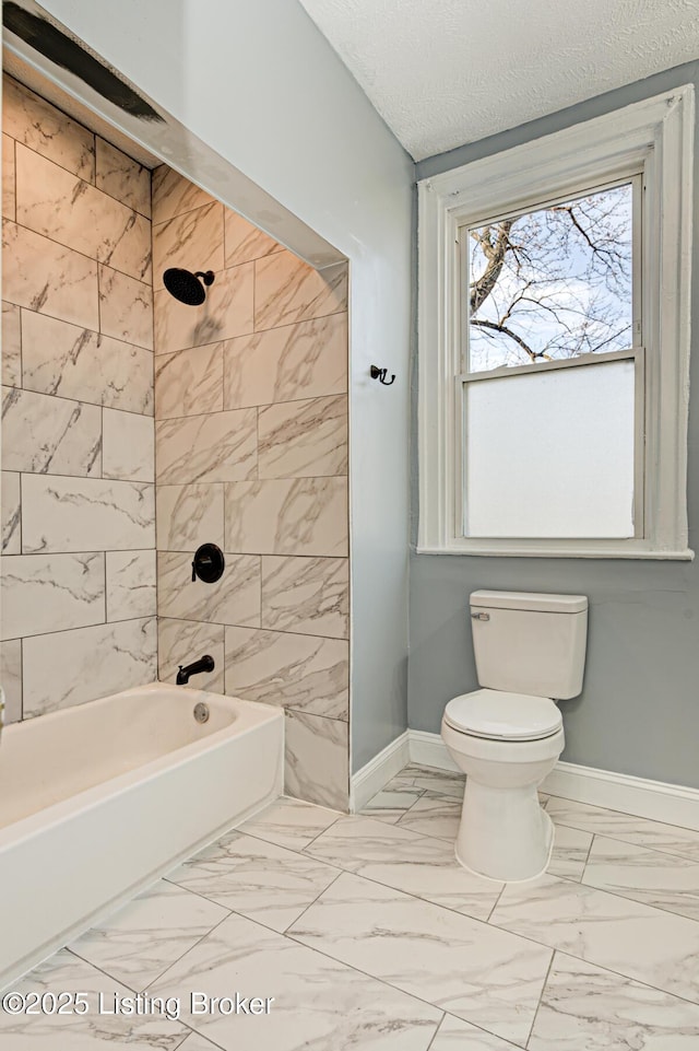 bathroom with tiled shower / bath combo, a textured ceiling, and toilet