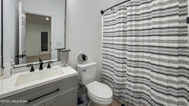 bathroom with walk in shower, vanity, and toilet