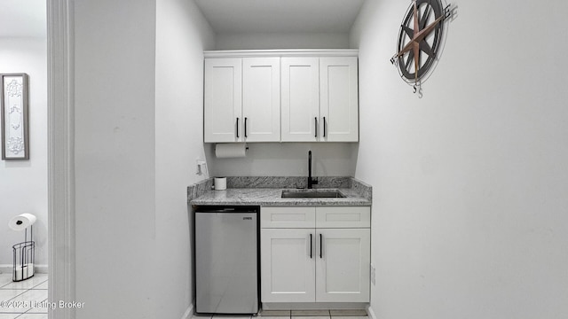 bar with stainless steel refrigerator, white cabinetry, sink, and light tile patterned floors