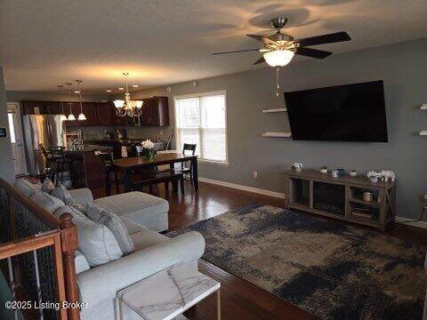 living room featuring dark wood-type flooring and ceiling fan with notable chandelier