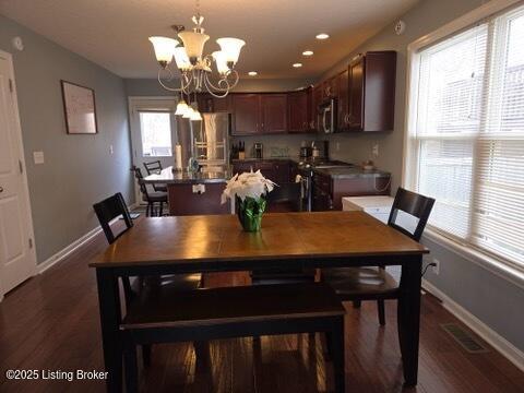 dining area with dark wood-type flooring and an inviting chandelier