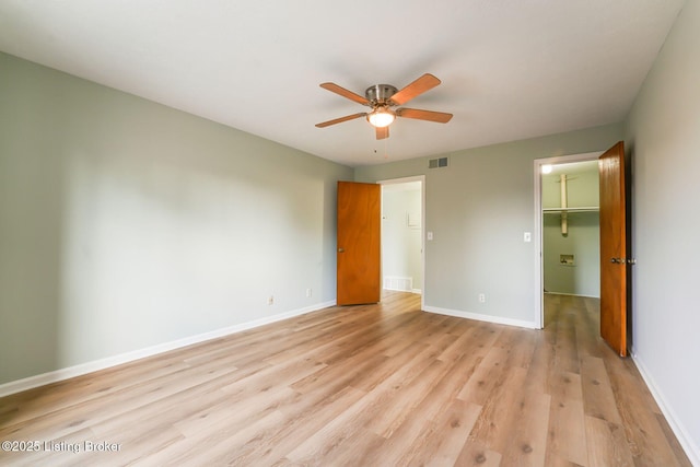 unfurnished bedroom featuring visible vents, baseboards, a closet, light wood-type flooring, and a walk in closet