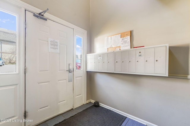 foyer entrance featuring baseboards and mail area