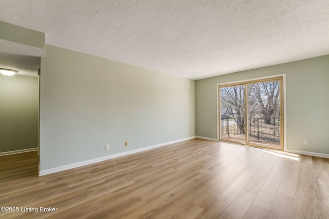 spare room with a textured ceiling, baseboards, and wood finished floors