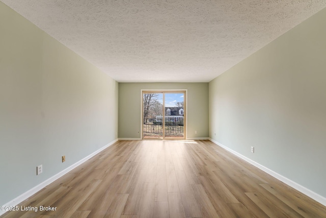 unfurnished room featuring a textured ceiling, wood finished floors, and baseboards