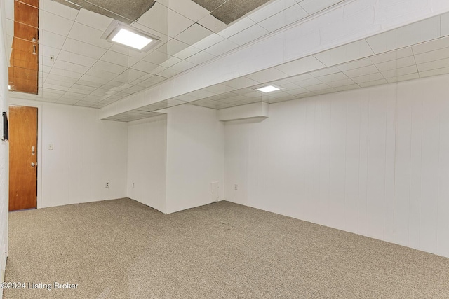 basement featuring a paneled ceiling and carpet flooring