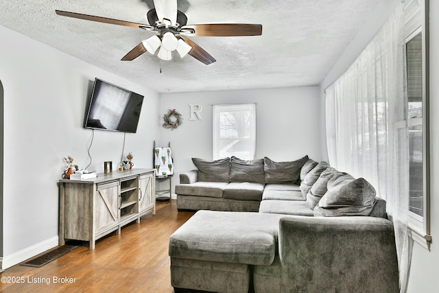 living room with hardwood / wood-style floors, a textured ceiling, and ceiling fan