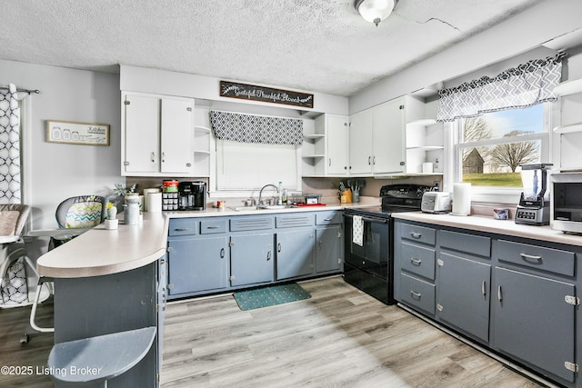 kitchen with sink, white cabinets, light hardwood / wood-style floors, and black / electric stove