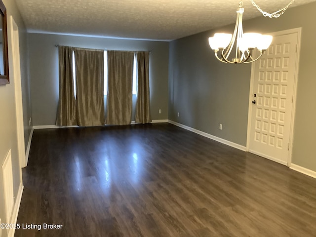 unfurnished room featuring dark wood-type flooring, a chandelier, and a textured ceiling