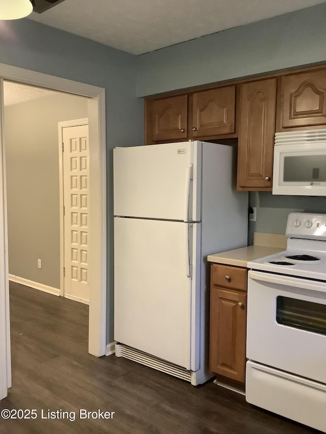 kitchen featuring white appliances and dark hardwood / wood-style floors