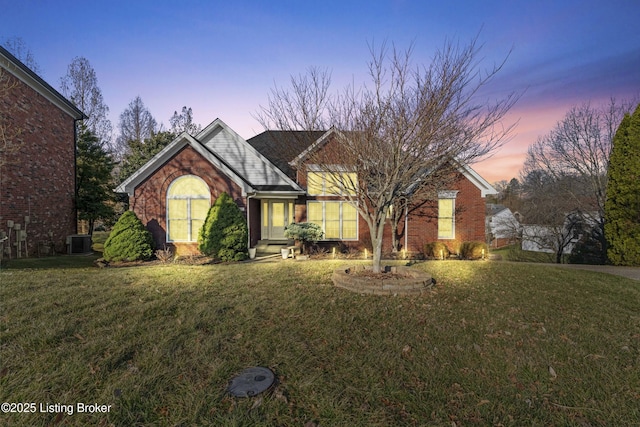 view of front facade with a front yard, brick siding, and central AC