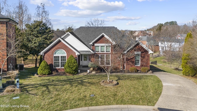 view of front facade featuring brick siding, a front yard, and roof with shingles