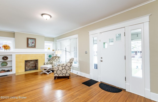 foyer entrance featuring hardwood / wood-style flooring, crown molding, and a fireplace