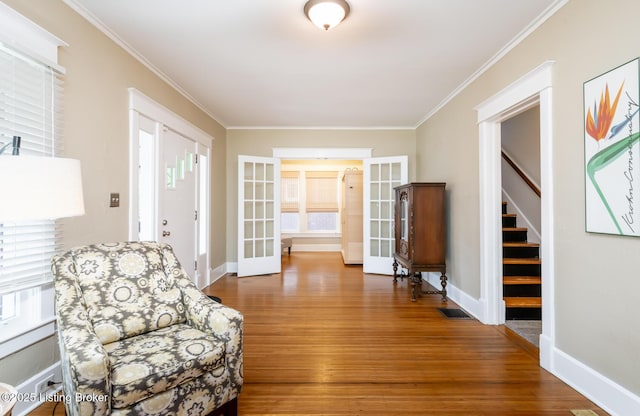 living area featuring hardwood / wood-style flooring, ornamental molding, and french doors