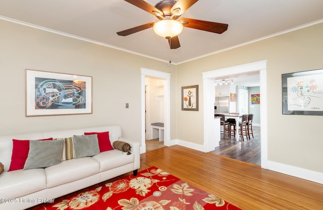 living room featuring ornamental molding, wood-type flooring, and ceiling fan