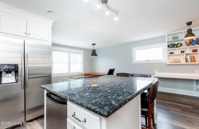 kitchen featuring stainless steel refrigerator with ice dispenser, dark stone counters, a breakfast bar, and white cabinets