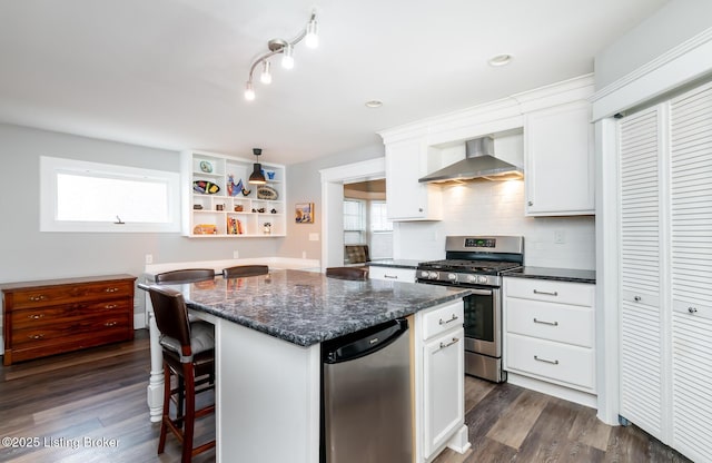 kitchen featuring a kitchen island, appliances with stainless steel finishes, white cabinetry, dark hardwood / wood-style flooring, and wall chimney exhaust hood